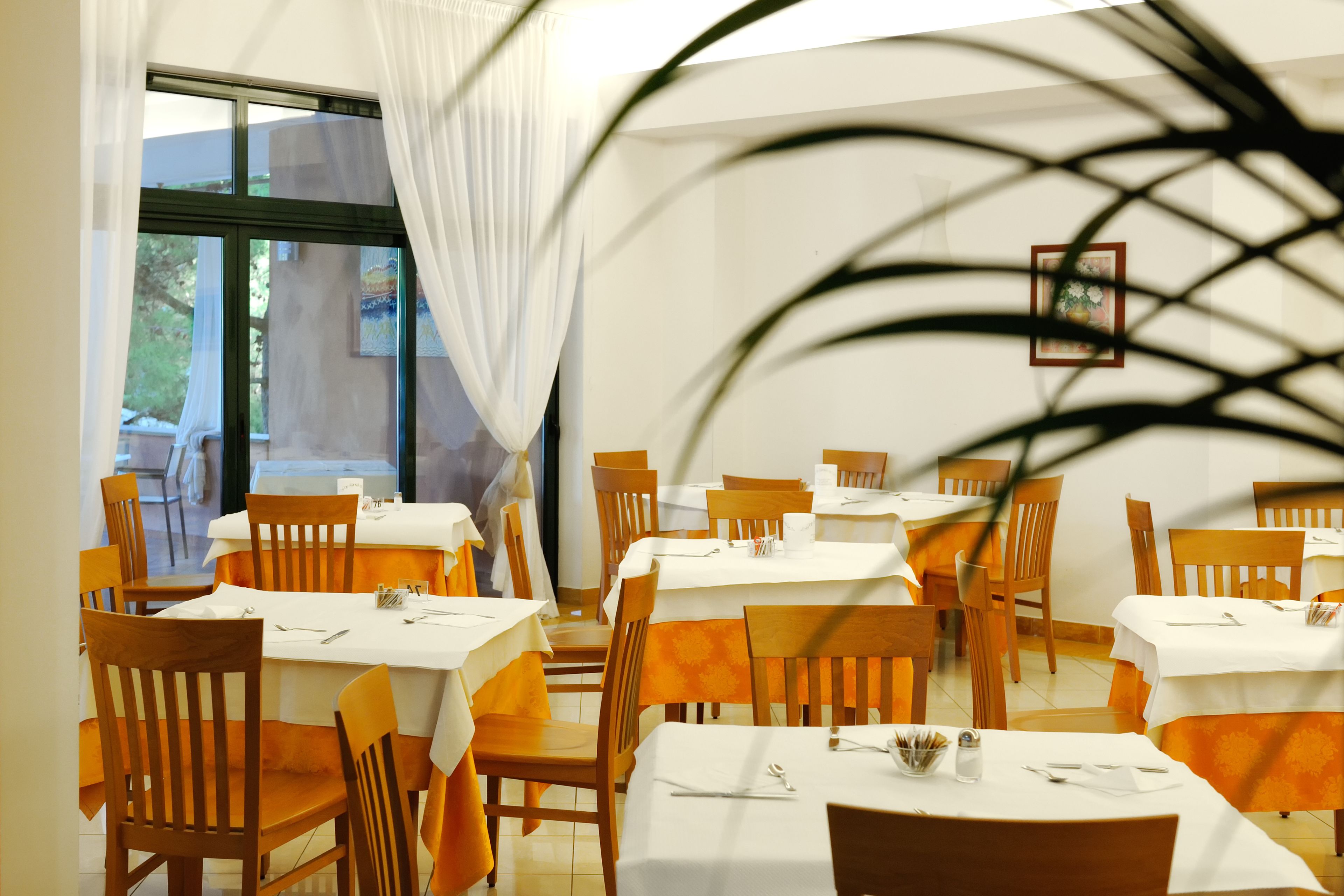 Un restaurante con varias mesas y sillas, dispuesto en un espacio amplio con vistas al exterior.