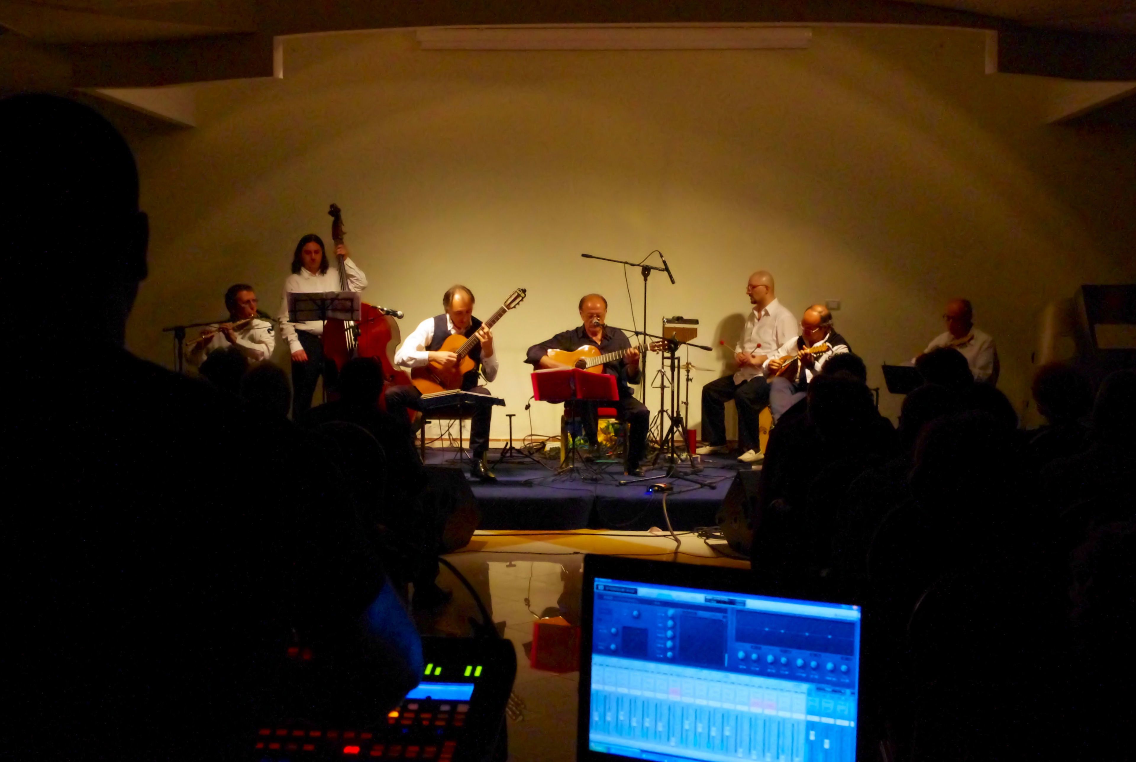 A band performing on a stage with a crowd in front.