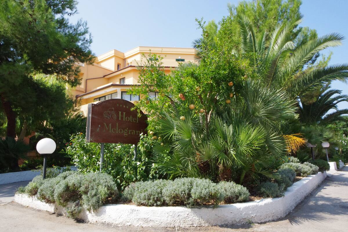 A sign for a hotel with a garden in front.