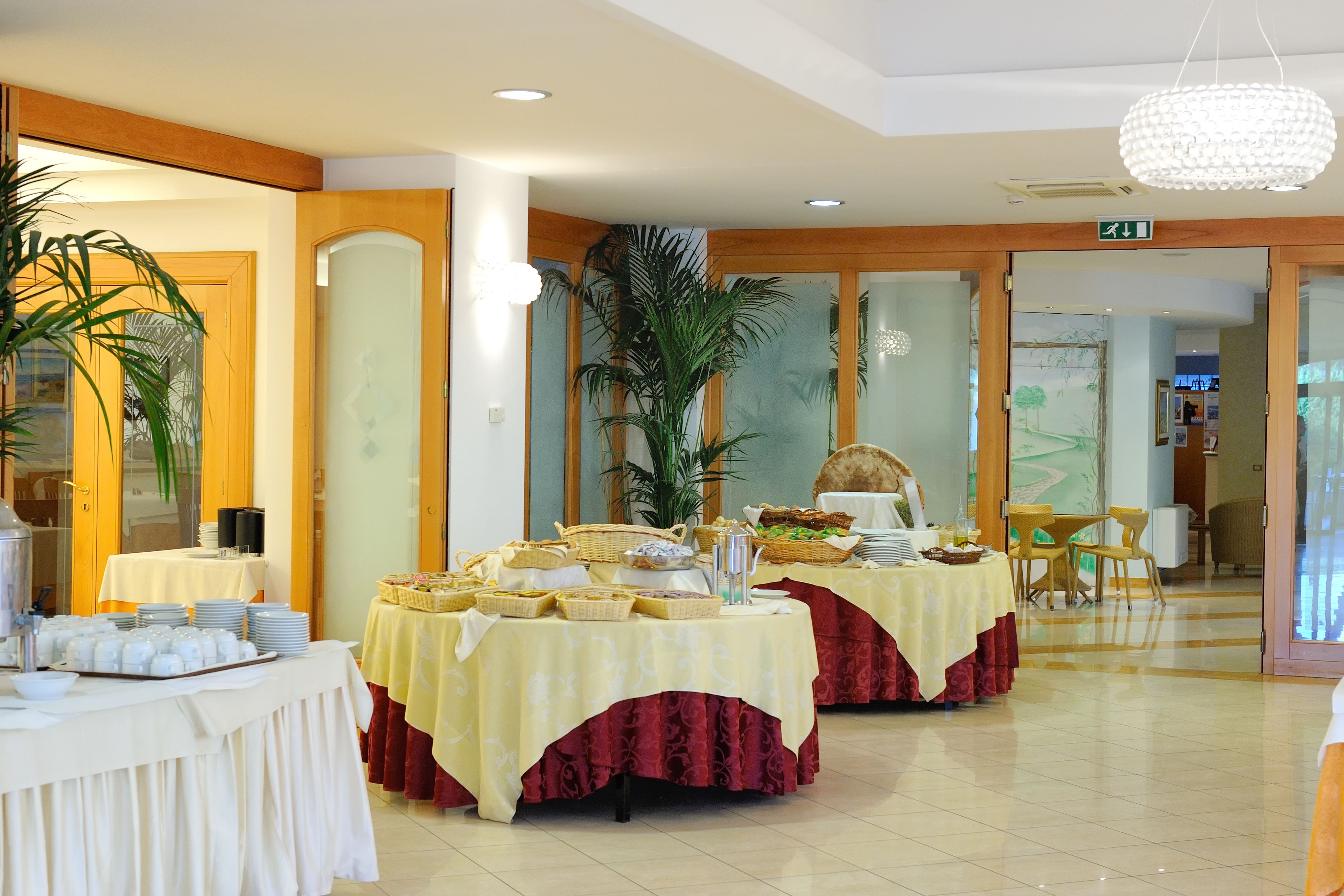 Un salón de banquetes con mesas dispuestas para un bufé, que incluye diversos alimentos y utensilios para servir.