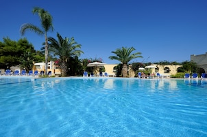 Una piscina al aire libre, sombrillas, sillones reclinables de piscina