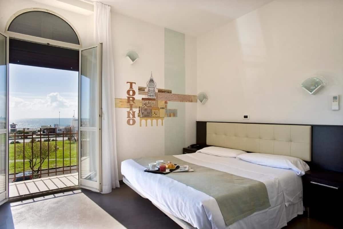 Una habitació d'hotel amb llit, vistes a la ciutat i un balcó.