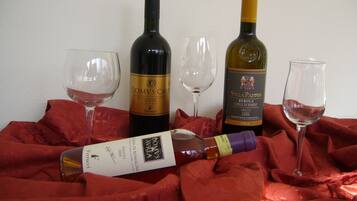 Three wine bottles and two wine glasses on a red cloth.