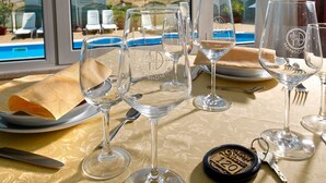 Una mesa con copas de vino y servilleta, con vista a una piscina y una playa.