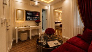 A hotel room with a TV displaying 'Stranger Things', a vanity with a mirror, a bedside table with a newspaper, and a red velvet sofa. - Ayasofya Hotel - Special Class (Istanbul)