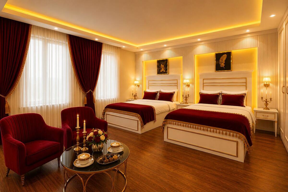 A hotel room with two beds, a sitting area with a table, and a view of the city.