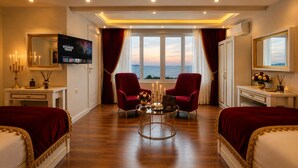 Habitación de hotel con dos camas, televisión, escritorio, espejo y vista al mar.