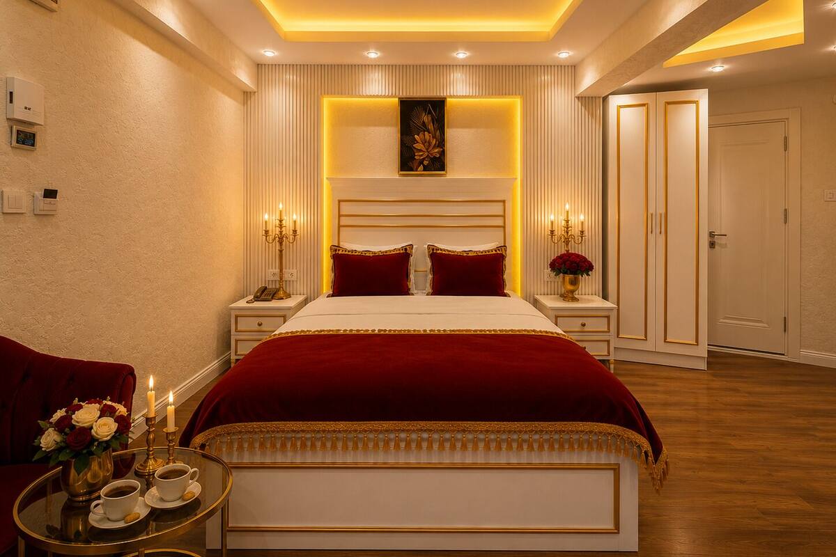 A modern bedroom with a large bed, bedside tables, a nightstand, a mirror, and a door.