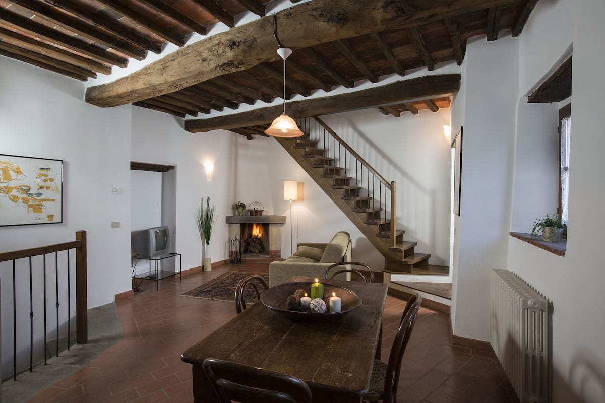Un'atmosfera rustica con un tavolo da pranzo in legno, un camino, un divano e una scala.