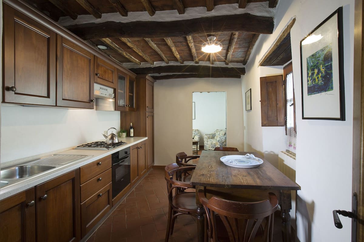 Una cucina con mobili in legno, un fornello e un'area pranzo con tavolo e sedie.