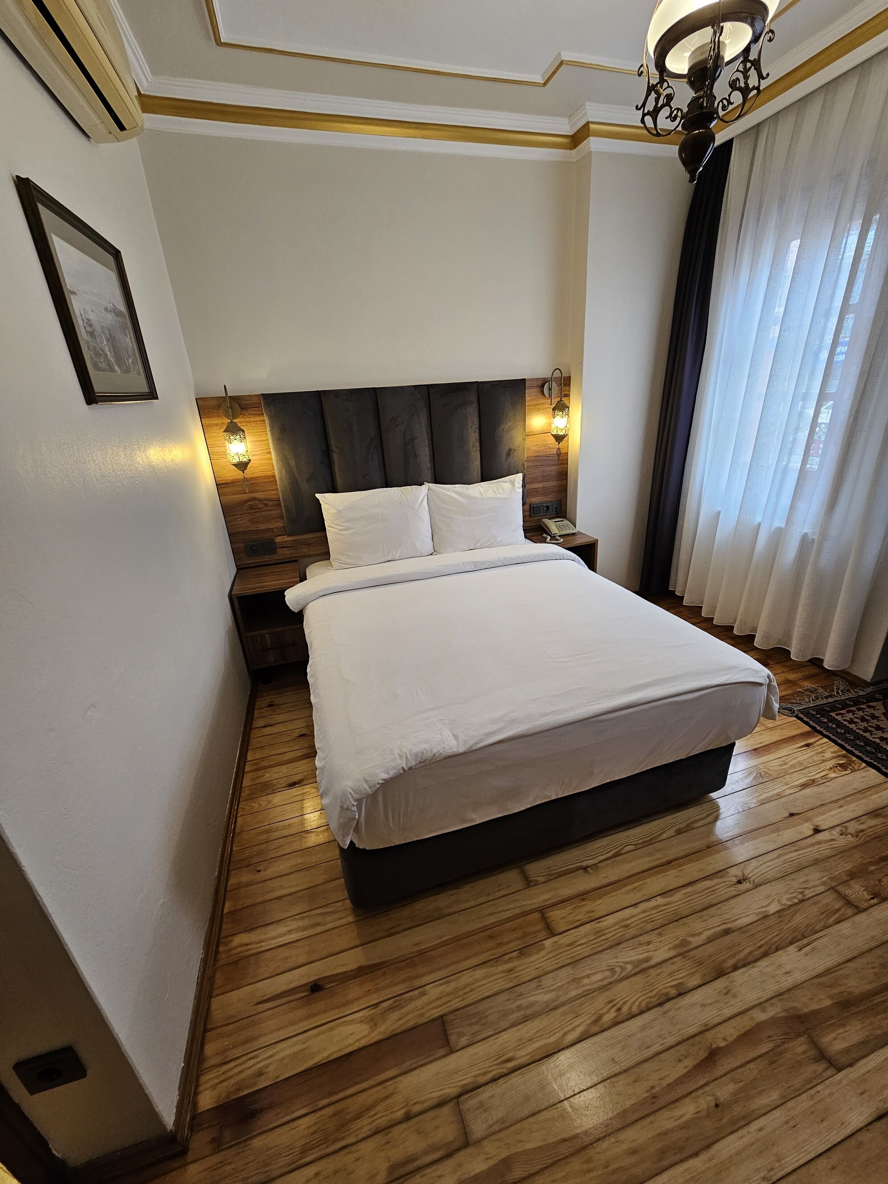 Une chambre à coucher bien aménagée, avec un grand lit, une tête de lit en bois et deux lampes fixées au mur.