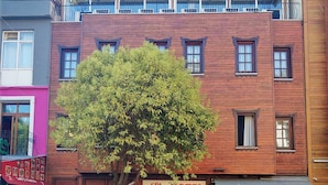 Un hôtel avec une façade en bois, de grandes fenêtres et un arbre devant.