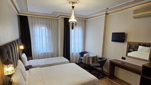 Une chambre d’hôtel avec deux lits, un bureau, une chaise, une télévision et un lustre.