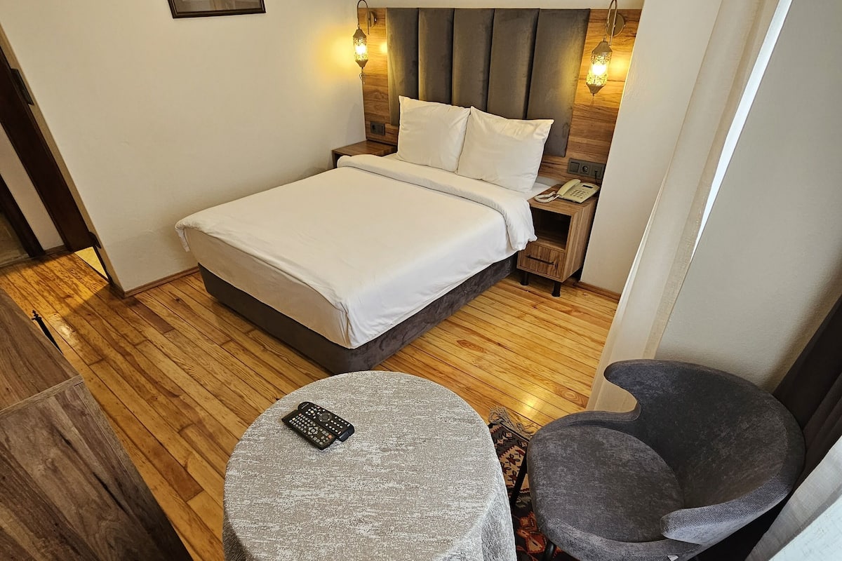 Une chambre à coucher avec un lit, des lampes de chevet, une petite table et deux chaises.
