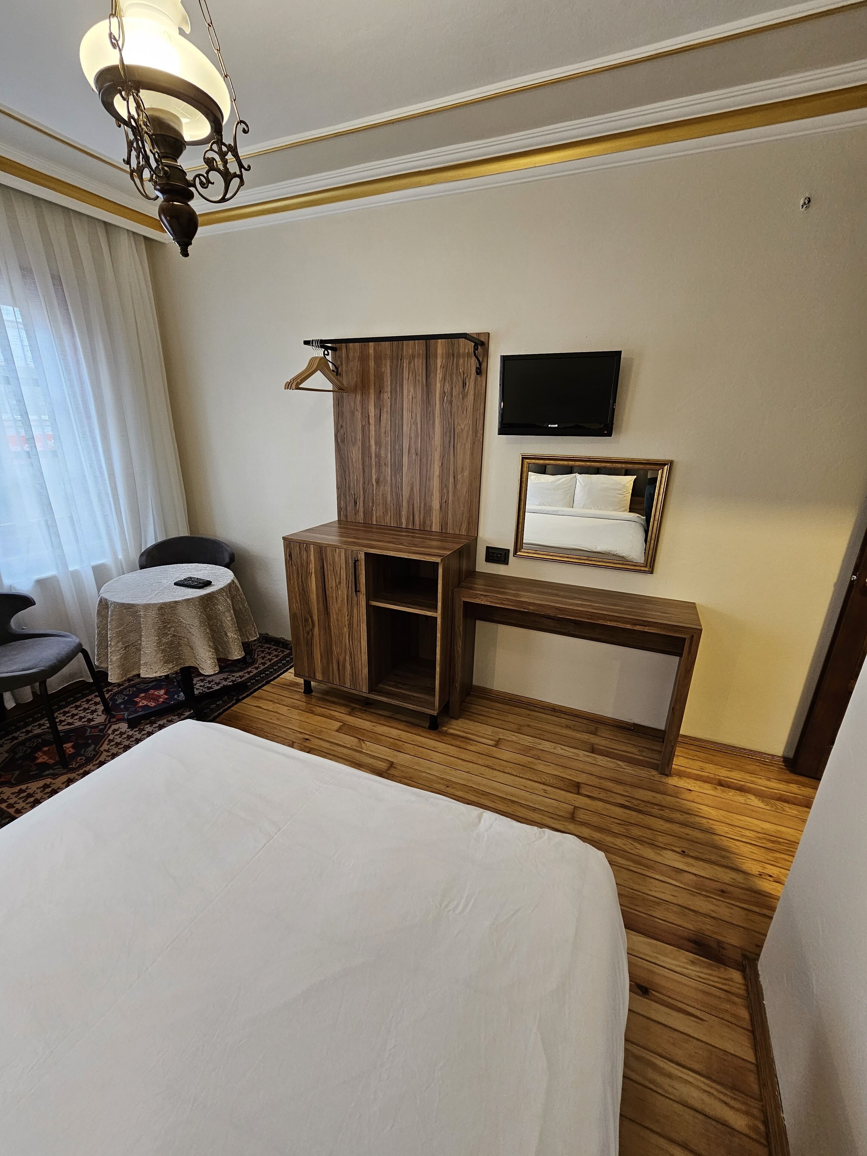 Een hotelkamer met een groot bed, een houten bureau, een televisie en een kledingkast.