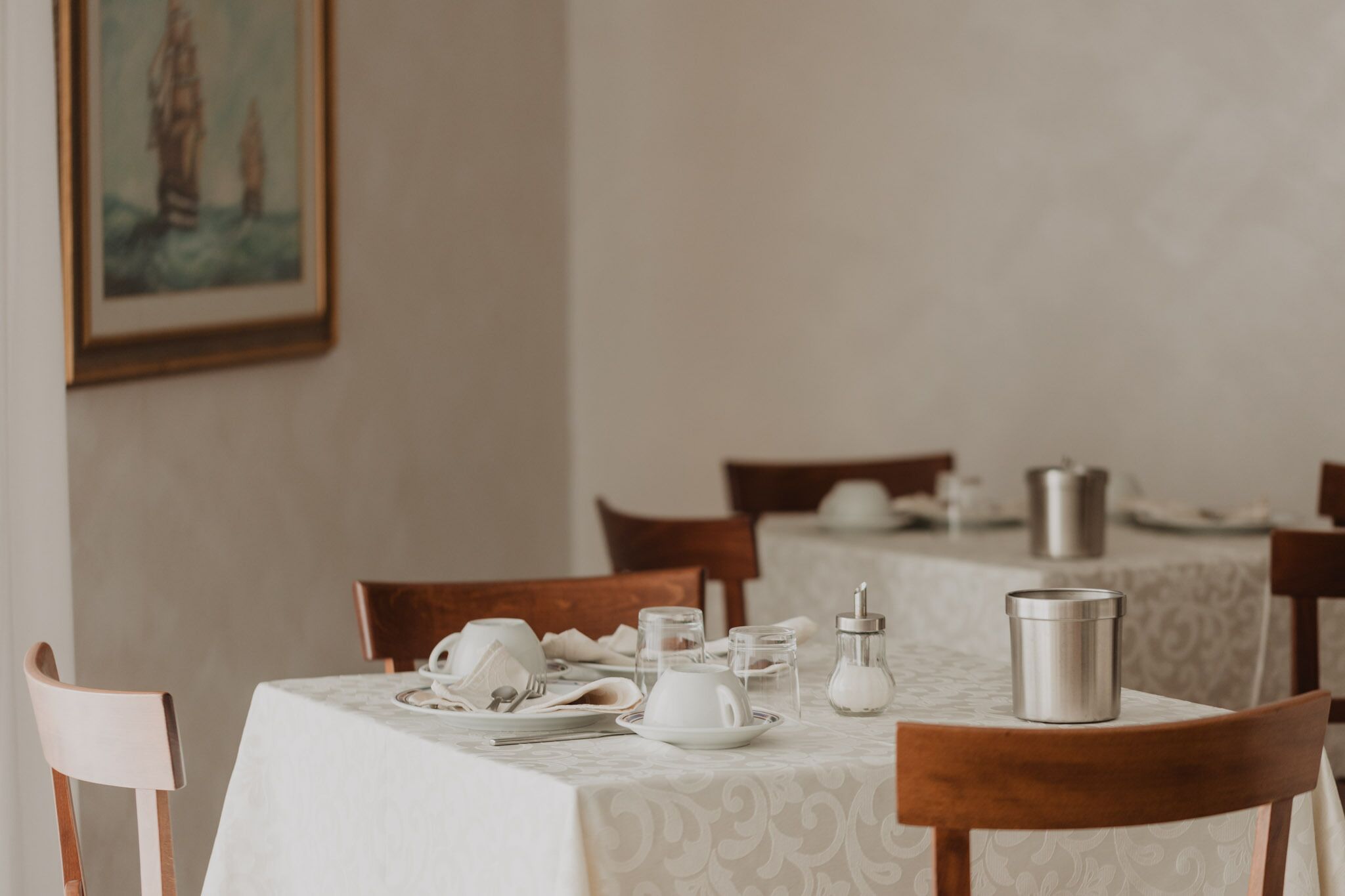 Un coin repas avec une table dressée pour deux personnes, comprenant des assiettes, des couverts et un thermos.