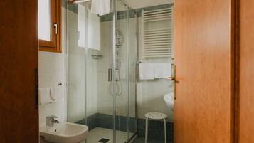 A bathroom with a glass-enclosed shower, a sink, and a toilet.