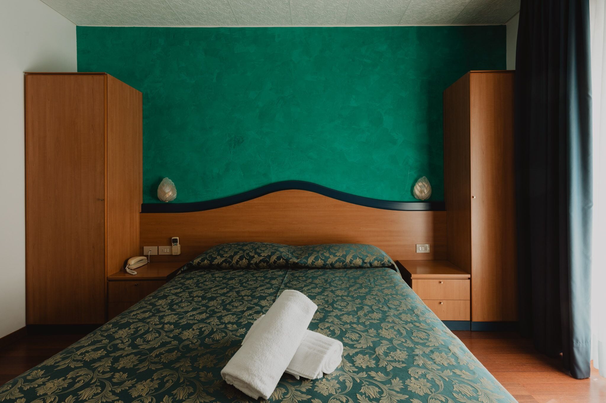 Ein Hotelzimmer mit einem Bett, einem Holzschrank und einer grünen Wand.