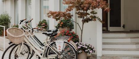 Una bicicleta amb un cistella i un senyal que indica el número 2, aparcada davant d'un edifici amb escales i plantes en testos.