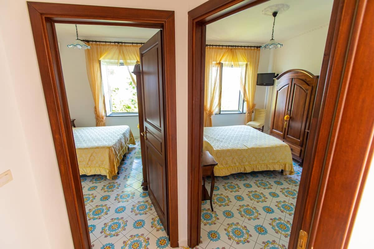 A room with two beds, wooden furniture, and patterned floor tiles.