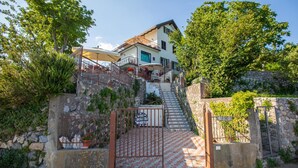 A two-story house with a stone staircase leading to a gated entrance. - Nido degli Dei (Agerola)