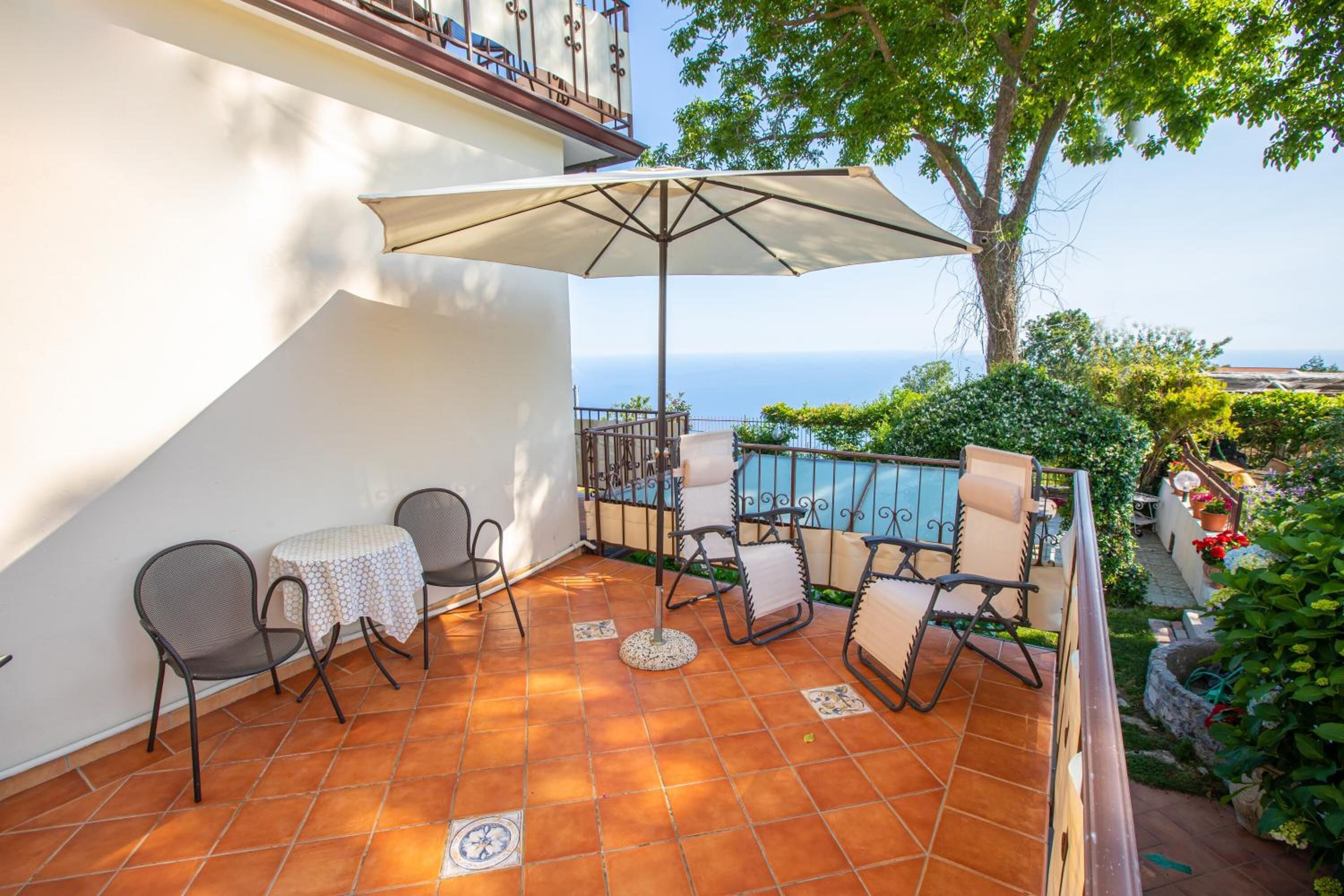A terrace with outdoor seating, a pool, and a view of the sea.