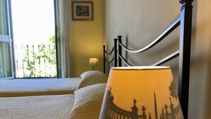A bed with a quilted cover, a lamp with a silhouette design, and a window with curtains. - Il Tesoro (Rome)