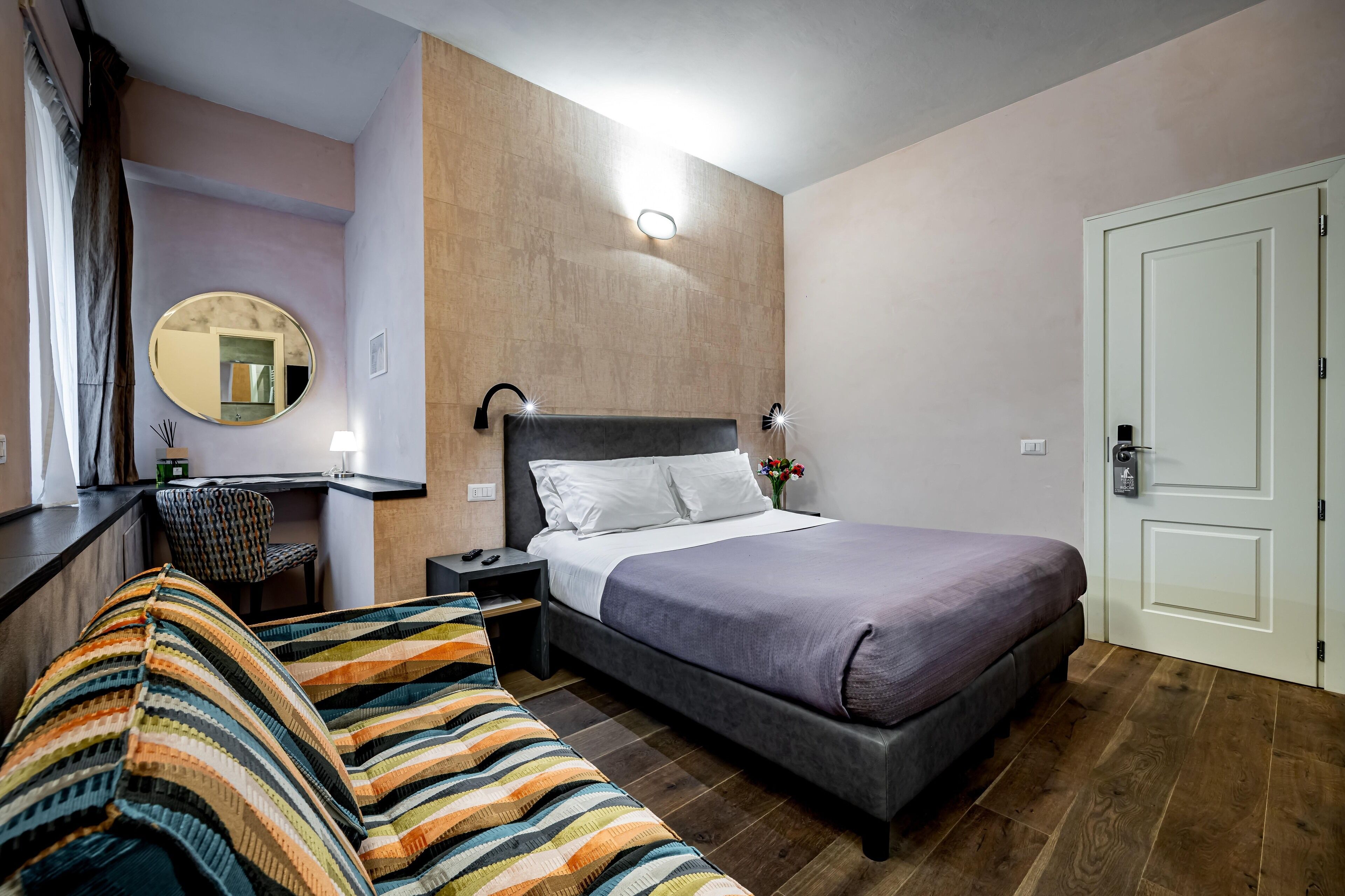 Un dormitorio con cama, mesita de noche, silla y espejo.