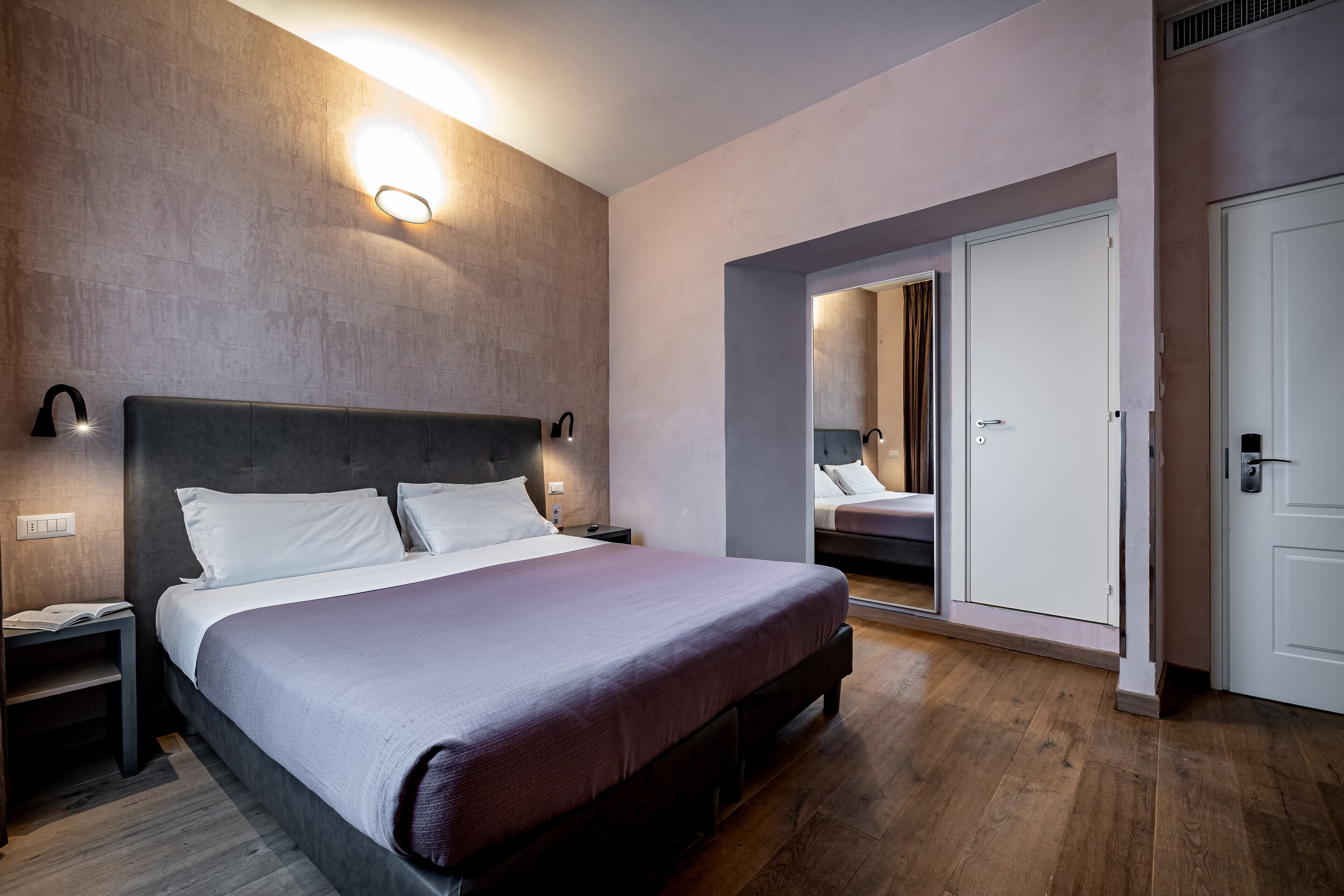 Ein modernes Hotelzimmer mit einem großen Bett, Nachttischen und einem Kleiderschrank.