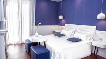 Un dormitorio moderno con una cama grande, dos mesitas de noche, un aparador blanco y un reposapiés azul.