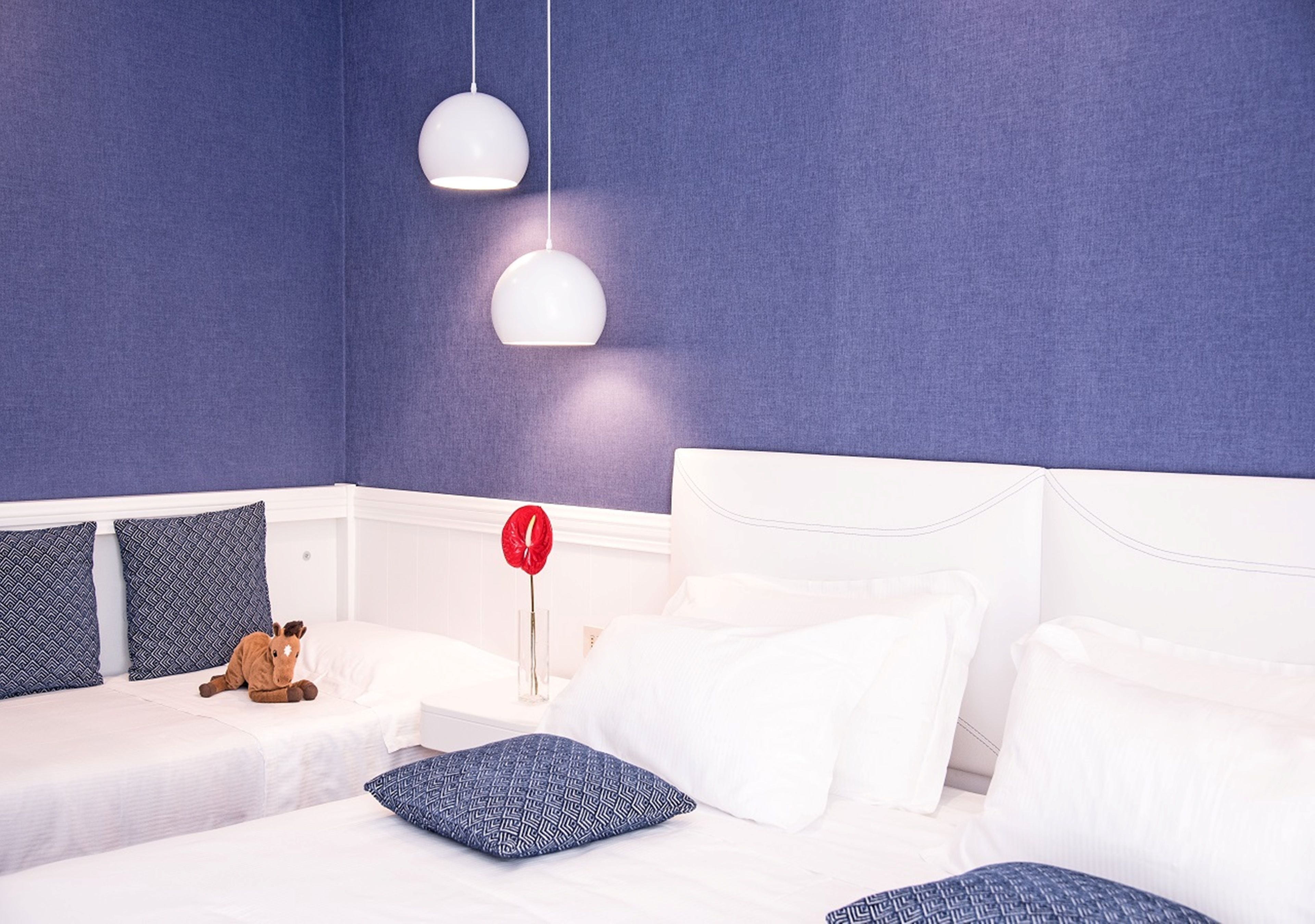 A hotel room with two beds, a headboard, and a nightstand with a red lipstick and a teddy bear.