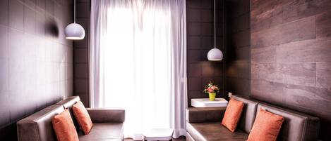 Una sala moderna con un sofá seccional, dos lámparas colgantes y un ventanal con cortinas.