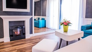A modern living room with a fireplace, a television, and a large window with curtains. - Ambienthotels Villa Adriatica (Rimini)