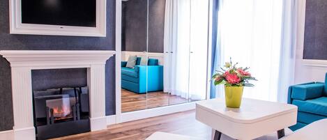 Una sala de estar moderna con chimenea, televisor y un ventanal con cortinas.