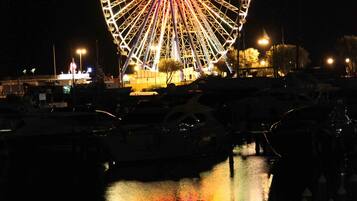 A large Ferris wheel at night with its lights reflecting on the water.