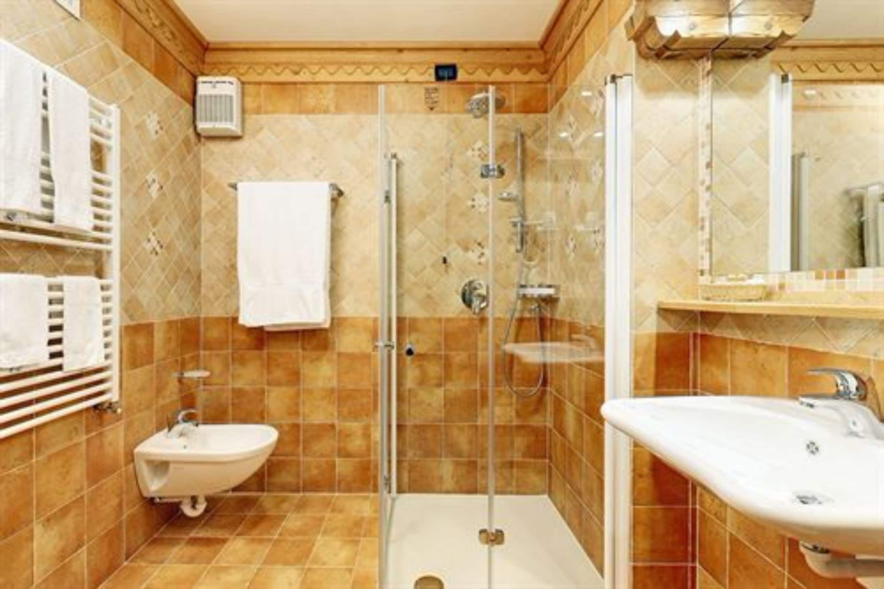 A bathroom with a glass-enclosed shower, a bidet, and a sink.