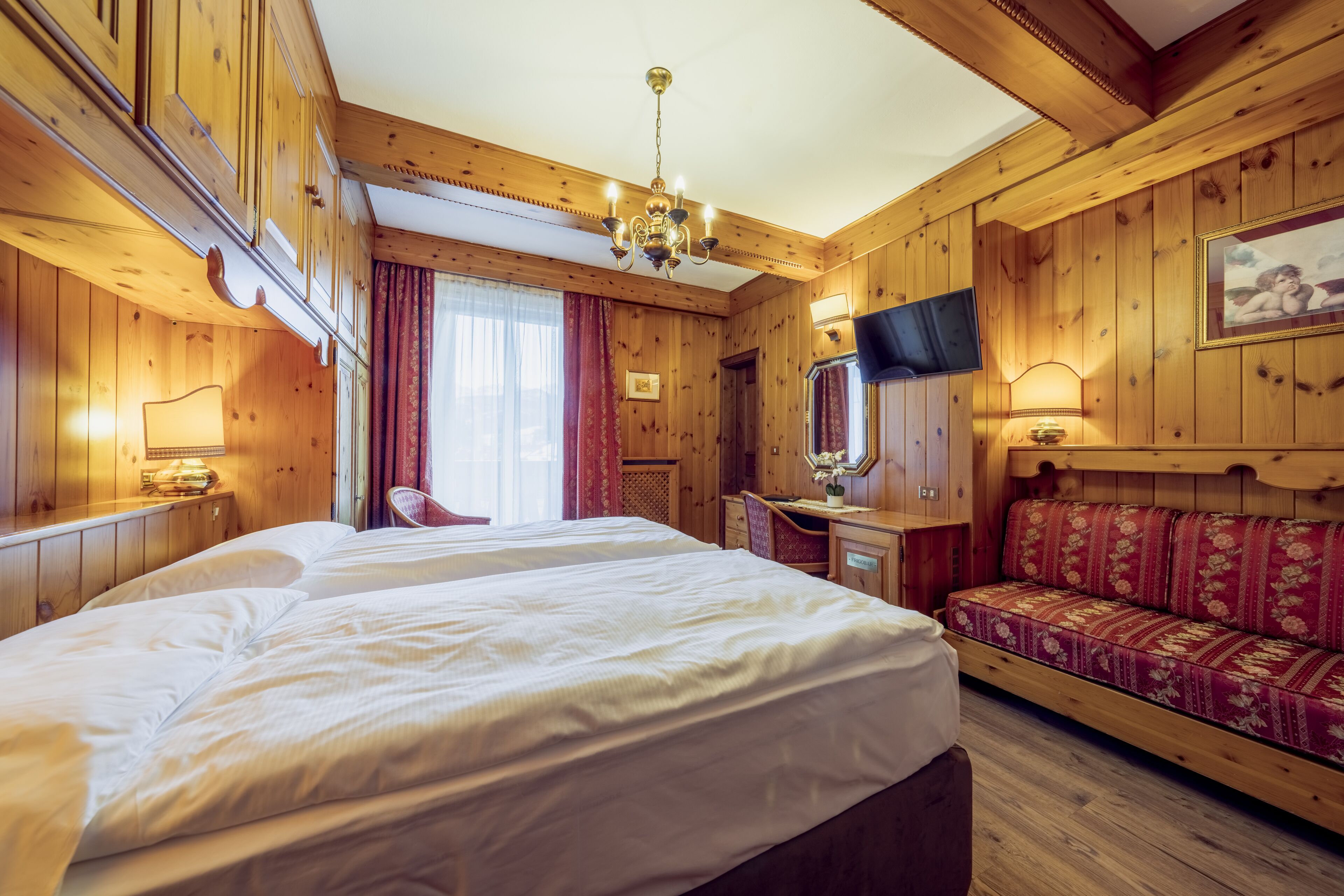 A wooden room with a large bed, a desk, a chair, and a sofa.