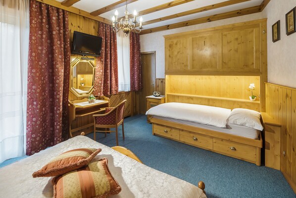 Un dormitorio con cama, escritorio y silla, espejo, televisor y paneles de madera.