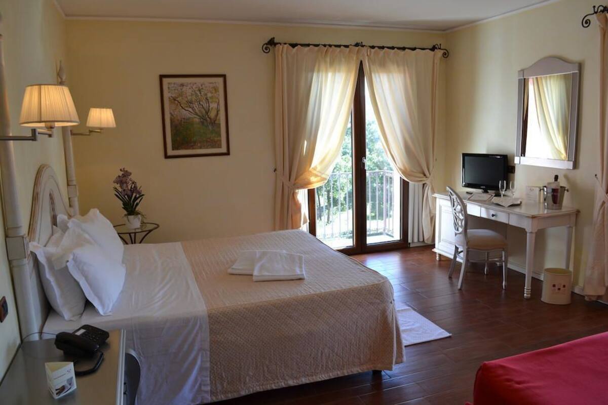 Ein Hotelzimmer mit Bett, Schreibtisch, Stuhl und Fernseher.