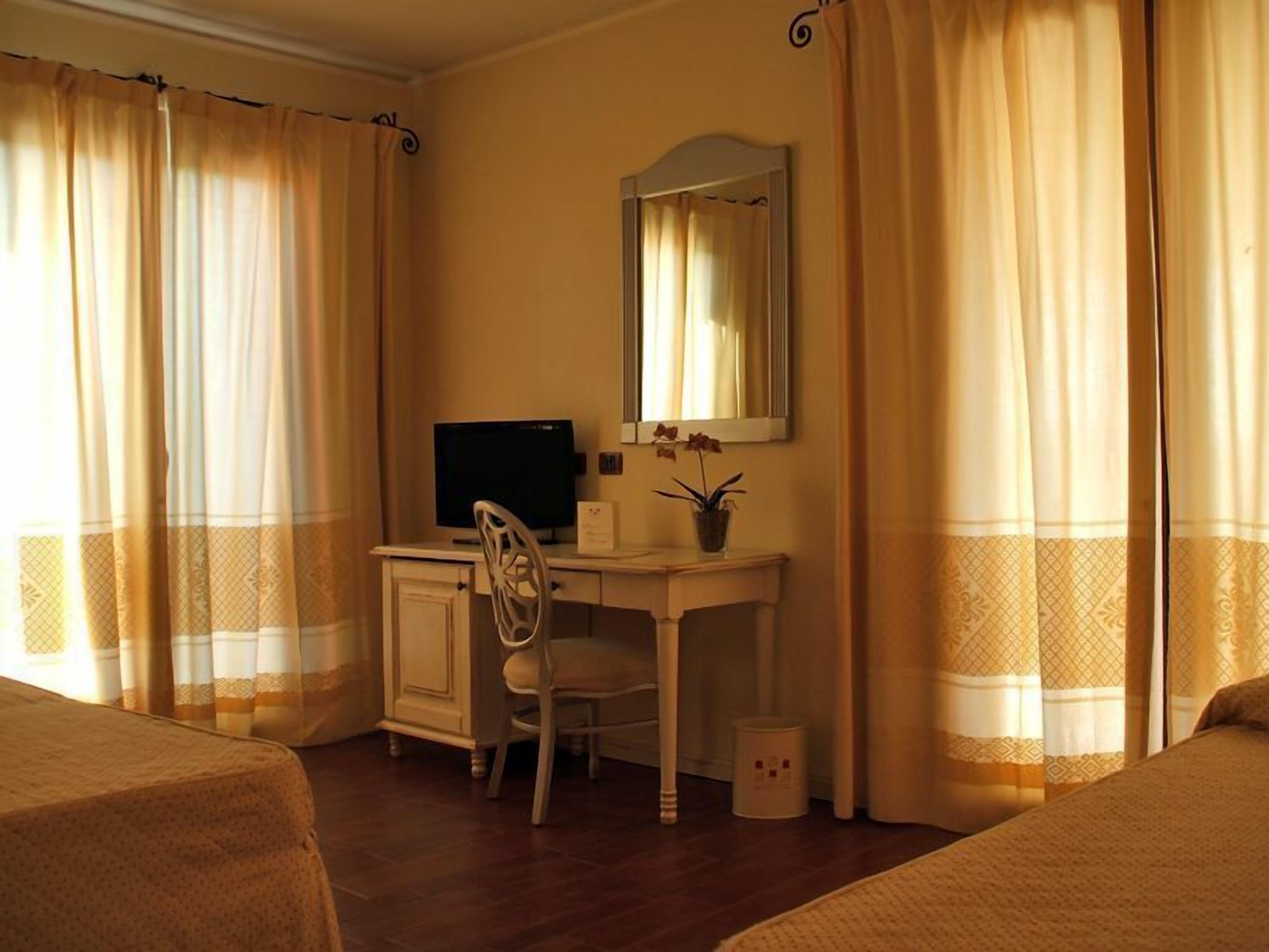 A hotel room with a desk, chair, and a bed.