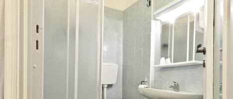 A bathroom with a toilet, bidet, sink, and a mirror.