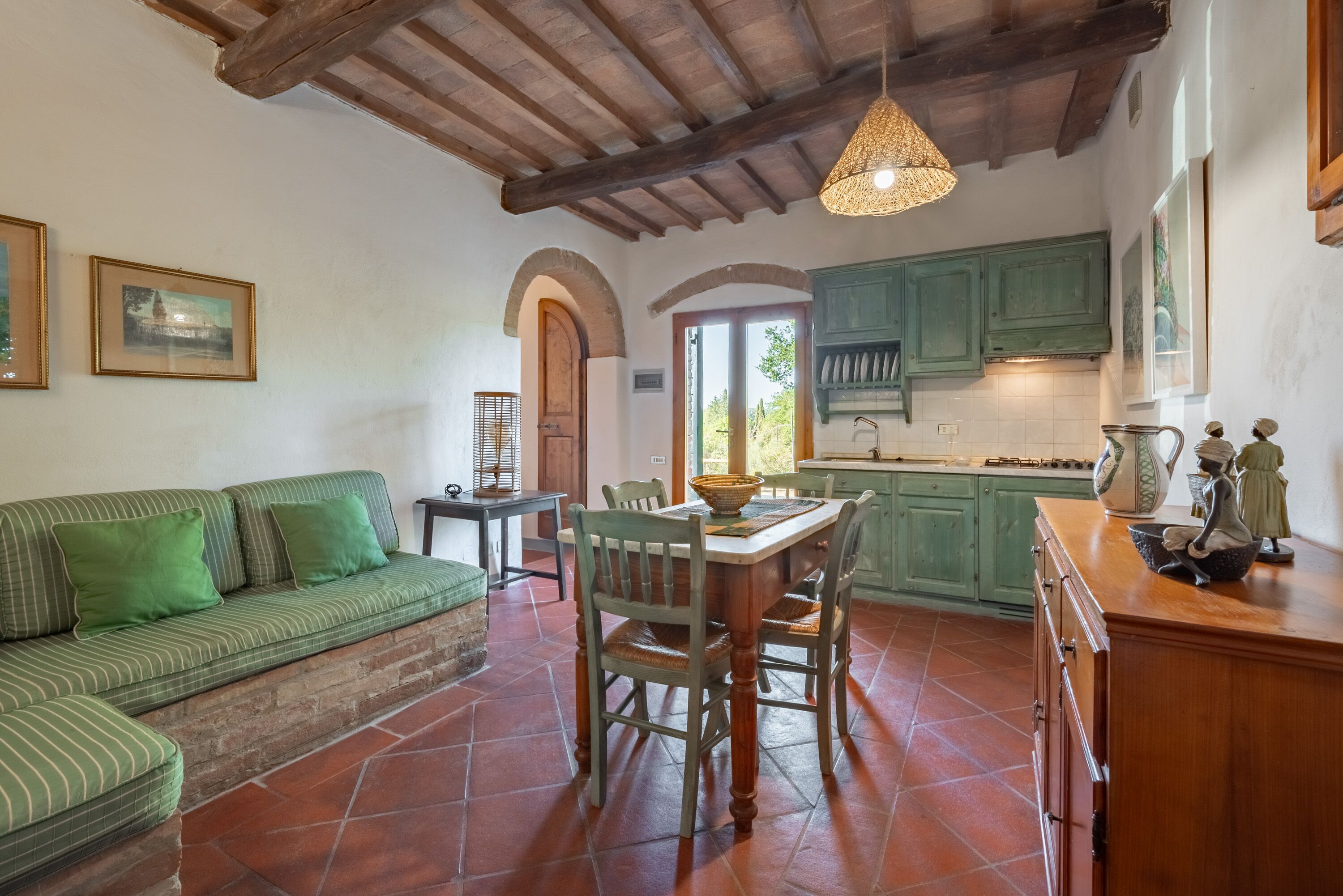 Una cocina acogedora con una mesa de comedor, sillas y un sofá verde.