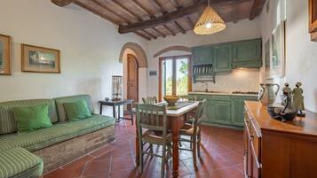 Una cocina acogedora con una mesa de comedor, sillas y un sofá verde.