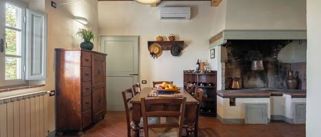 Una cocina rústica con una mesa de madera, sillas y suelo de ladrillo.