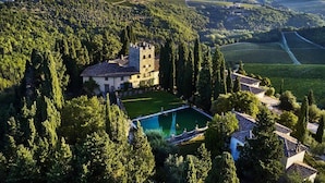 An aerial view of a castle-like building surrounded by lush greenery and vineyards. - Agriturismo Bio Fattoria Bacio (Certaldo)