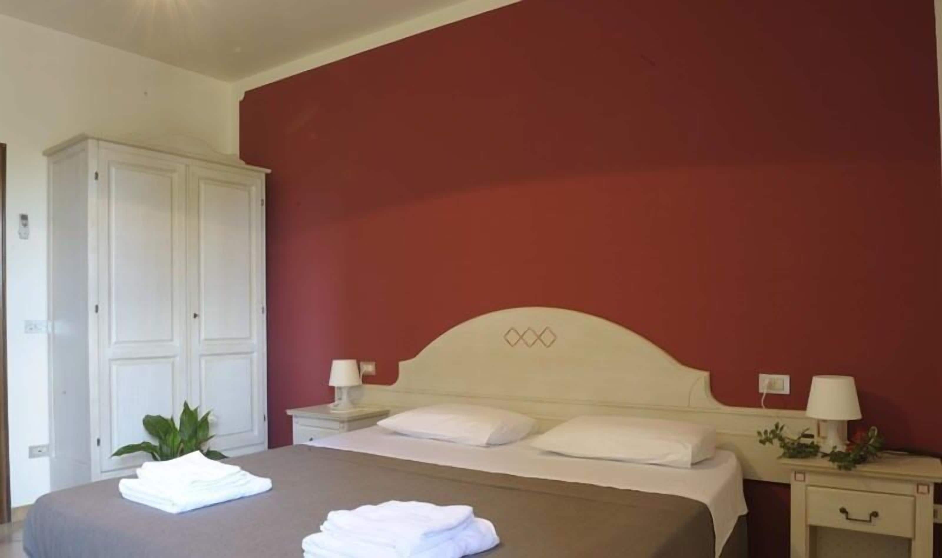 Une chambre à coucher avec un lit, deux tables de chevet avec des lampes, une armoire et une plante en pot.