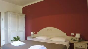 Une chambre à coucher avec un lit, deux tables de chevet avec des lampes, une armoire et une plante en pot.