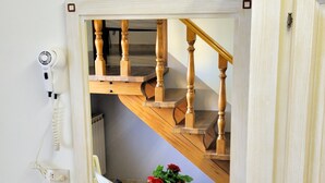 A room with a wooden staircase, a mirror, a desk with a telephone, and two red flower pots. - La Spiga (Campi Bisenzio)