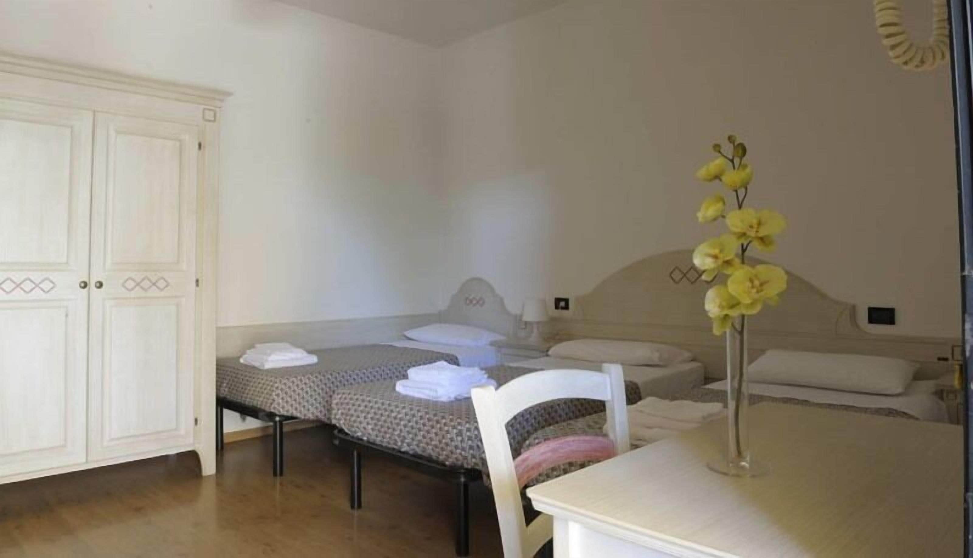 Una habitación pequeña y limpia con una cama, una silla, una mesa y un armario.