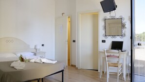 A hotel room with a bed, bedside tables, a desk with a chair, a mirror, and a television. - La Spiga (Campi Bisenzio)